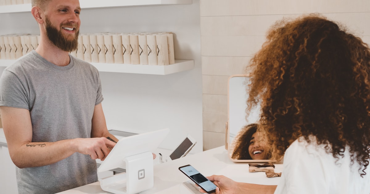 Artisan souriant accueillant une cliente derrière son comptoir